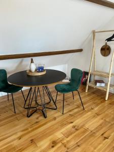 einen Tisch und zwei grüne Stühle in einem Zimmer in der Unterkunft Wanatan Chambre d'hôtes in Penmarcʼh