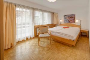 1 dormitorio con 1 cama, 1 silla y ventanas en Hotel Parnass, en Zermatt