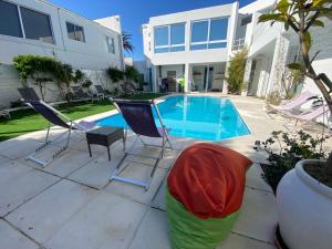 a patio with two chairs and a swimming pool at Peach on Beach Boutique Guesthouse in Bloubergstrand