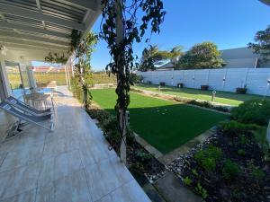 a patio with a lawn with a golf course at Peach on Beach Boutique Guesthouse in Bloubergstrand