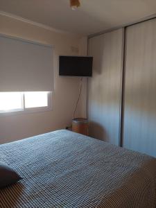 1 dormitorio con 1 cama y TV de pantalla plana en departamento chateau en Córdoba