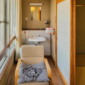 a bathroom with a chair next to a sink at Yufuin Monday 湯布院マンデー in Yufuin
