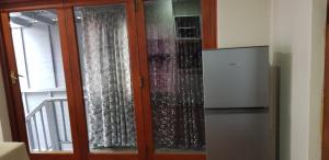 une porte coulissante en verre avec des rideaux et un réfrigérateur. dans l'établissement Neat Haven Self Catering, à Grahamstown
