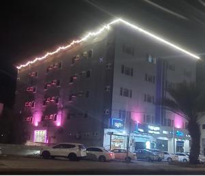 um edifício com carros estacionados em frente a ele à noite em اجنحة ارمادا em Al Qunfudhah