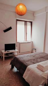 1 dormitorio con 1 cama, TV y lámpara en APPARTAMENTO LA SPIAGGETTA, en Foligno