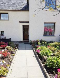 a walkway in front of a house with flowers at Nevis Rooms - Self check in with free onsite Parking in Inverlochy