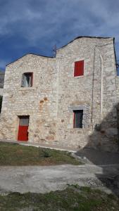 a stone building with red doors and windows at Πέτρινο σπίτι-Stone house in Koíta