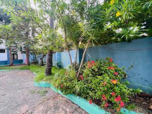 a garden with flowers and trees next to a wall at Hotel Sunday - Townhouse Club Airport Trivandrum in Trivandrum