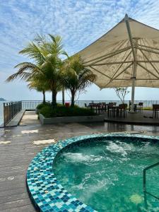 una piscina con sombrilla junto al océano en KUANTAN Imperium Residence, en Kuantan