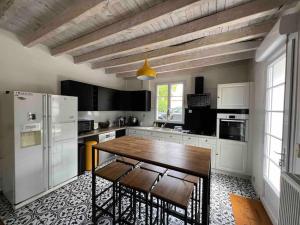 cocina con mesa de madera y electrodomésticos blancos en Maison de charme proche gare, en Le Gond