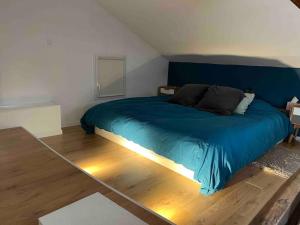 1 dormitorio con 1 cama azul y suelo de madera en Maison de charme proche gare, en Le Gond