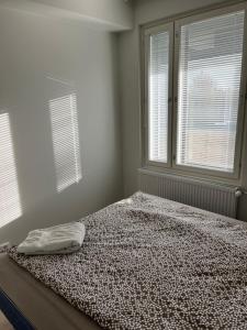 a bed in a bedroom with two windows at New built One bedroom Apartment nearby Train station in Vantaa