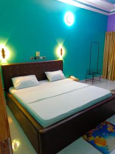 ein Schlafzimmer mit einem großen Bett mit blauer Wand in der Unterkunft HOTEL MAVILLA Cotonou in Cotonou