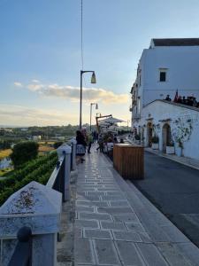 a street with a white building and people walking down the street at La Dimora nel Borgo in Locorotondo