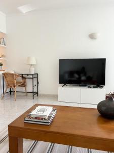 - un salon avec une grande télévision à écran plat sur une armoire blanche dans l'établissement Wait N Sea - T1 Salgados, à Guia