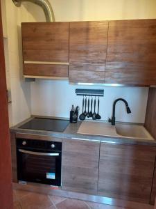 - une cuisine avec des placards en bois, une cuisinière et un évier dans l'établissement Casa vacanza Petrari Residence Alt Air, à Ovindoli