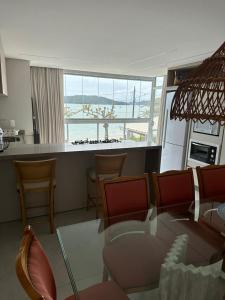 a living room with a table and chairs and a kitchen at Apartamento Frente Mar na Baía de Porto Belo in Porto Belo