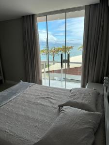 a bedroom with a bed with a view of the ocean at Apartamento Frente Mar na Baía de Porto Belo in Porto Belo