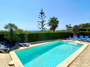 una piscina con sillas y el océano en el fondo en Villa Catalina Stunning 4bedroom villa with air conditioning sea views & private swimming pool ideal for families, en L'Ametlla de Mar