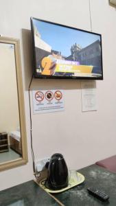 a television on a wall with a helmet on a table at SUSAN HOTEL SEAFRONT in Sandakan