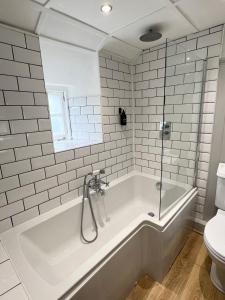 ein weißes Bad mit einer Badewanne und einem WC in der Unterkunft Hurst cottage, a cosy 2 bed cottage in Dorset in Stalbridge