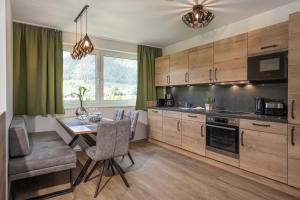 a kitchen with wooden cabinets and a table with chairs at AlpenParks Montana Apartments in Matrei in Osttirol