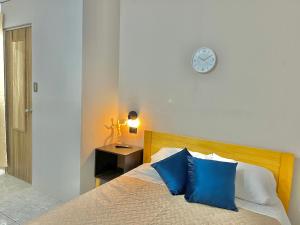 een slaapkamer met een bed met blauwe kussens en een klok bij Citadin Yurrita in Guatemala