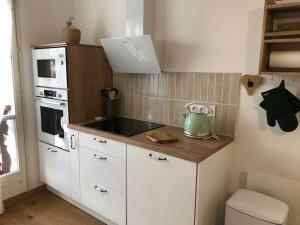 a kitchen with white cabinets and a green kettle on a counter at LE COEUR DE GERARDMER F2 PLEIN CENTRE 4P + GARAGE in Gérardmer