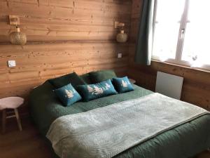 a bedroom with a green bed with blue pillows at LE COEUR DE GERARDMER F2 PLEIN CENTRE 4P + GARAGE in Gérardmer