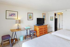 a bedroom with a bed and a desk with a television at Island Colony 4218 in Honolulu
