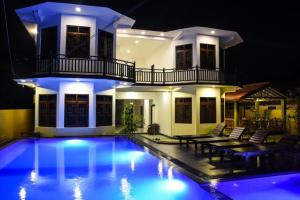 a large house with a swimming pool at night at Mamma Raji Hotel - Freedom Paradise in Negombo