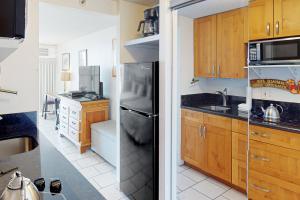 uma cozinha com armários de madeira e um frigorífico preto em Island Colony 4218 em Honolulu
