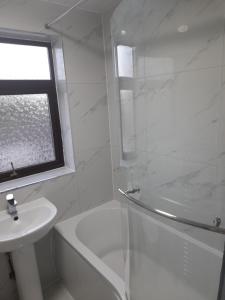 uma casa de banho branca com um chuveiro e um lavatório. em London Luxurious Sweet Home em Londres