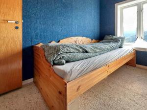 ein Holzbett in einem blauen Zimmer mit Fenster in der Unterkunft Holiday home Snillfjord II in Snillfjord