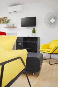 サン・タヴェルタンにあるGîte le Saint-Honoréの黄色い椅子2脚とテレビが備わる客室です。