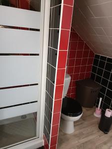uma casa de banho com um WC e uma parede de azulejos vermelhos em La Chataigneraie em Vernouillet