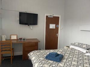赫爾河畔京士頓的住宿－earlsmere hotel，一间卧室配有一张床、一张书桌和一台电视