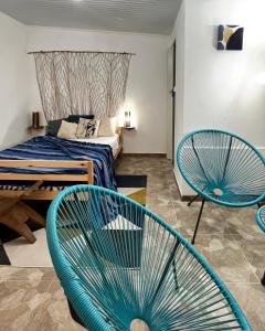 ein Schlafzimmer mit zwei blauen Stühlen und einem Bett in der Unterkunft Logis Colibri du Morne Jacob, Le Morne-Rouge Martinique in Le Morne Rouge
