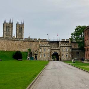 um edifício antigo com um portão e um campo verde em The Maisonette - Cultural Quarter - with parking! em Lincolnshire