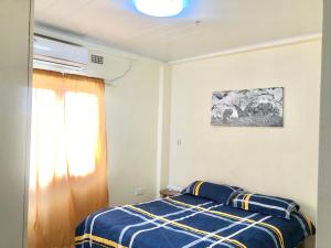 a bedroom with a bed with a blue and yellow blanket at LouieVille One Bedroom Apartment in Lusaka