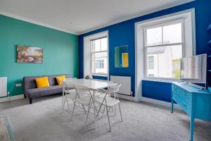 een woonkamer met blauwe muren en een tafel en stoelen bij One-Bedroom Apartment: Sleeps 4 Comfortably in Berwick-Upon-Tweed