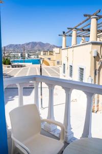 a white chair on a balcony with a view of a building at P i g a d i a B a y in Karpathos Town