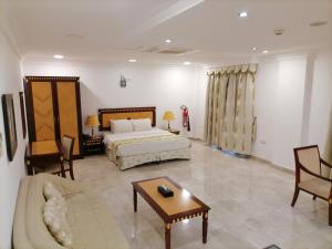 a bedroom with a bed and a couch and a table at Pioneer Hotel Apartments Muscat in Muscat