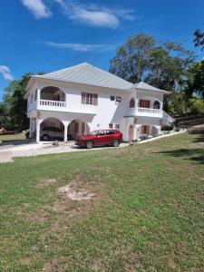 een rode auto geparkeerd voor een wit huis bij Shaw Park Gem Apt 12D in Ocho Rios