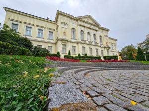 a large building with a stone walkway in front of it at Roman Apartman in Sremska Mitrovica