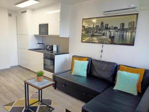 a living room with a black couch and a table at Apartament z balkonem Gliwice Mewy, klimatyzacja in Gliwice