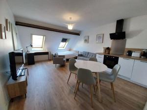 a living room with a table and chairs and a kitchen at Studio Babylone - Parking & Wifi in Chartres