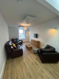 a living room with two leather couches and a tv at Substantial 5 Bed Townhouse in Peterhead