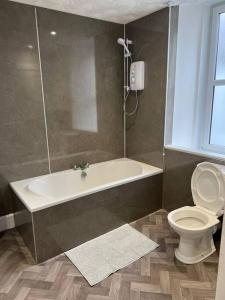 a bathroom with a bath tub and a toilet at Substantial 5 Bed Townhouse in Peterhead