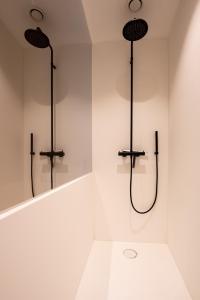 a white bathroom with two shower fixtures on a wall at Dunvegan in Ostend